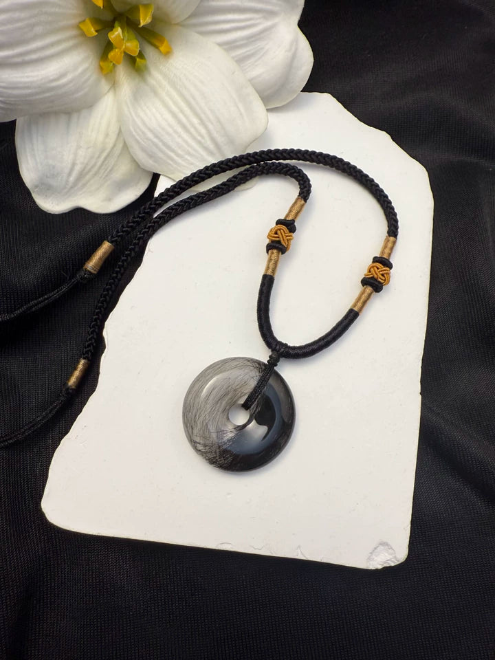 Dark pet fur arranged inside a clear round pendant with a black cord