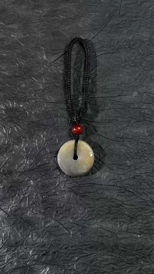 Light pet fur preserved in a small clear round pendant on a dark background