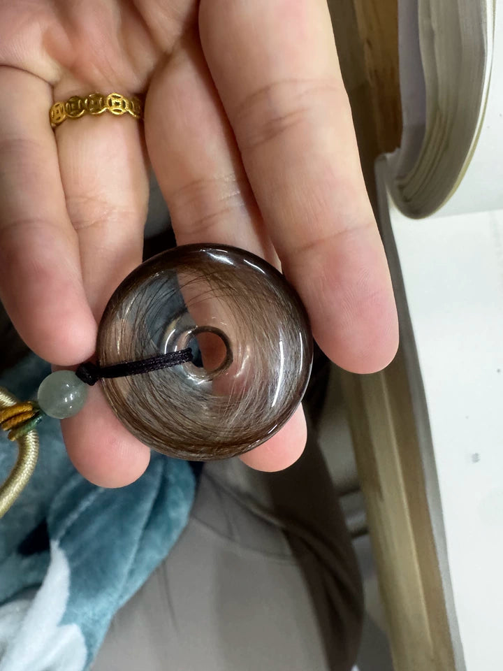 Close view of dark pet fur arranged in a polished clear round pendant